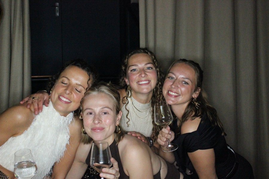 Vier vriendinnen met een glas wijn in de photobooth