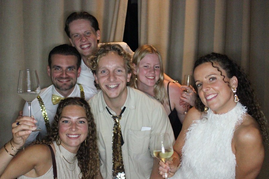 Groep feestgangers met glitterstrikjes in de photobooth